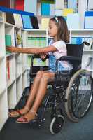 Disabled school girl selecting a book from bookshelf in library