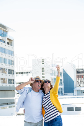 Couple taking selfie against sky in city
