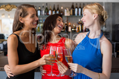 Happy female friends holding glass of champagne flute