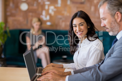 Business colleagues sitting on table and using laptop