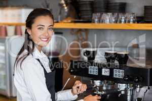 Portrait of smiling waitress making cup of coffee