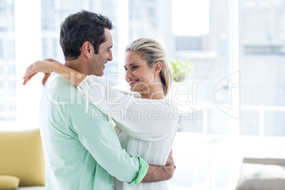 Mid adult couple hugging at home