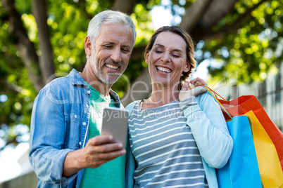 Mature couple using mobile phone by tree