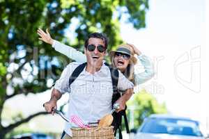 Cheerful couple riding bicycle on sunny day