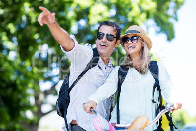 Man pointing while standing by woman with bicycle