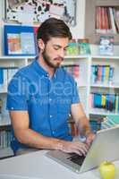 School teacher working on laptop in library