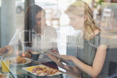 Women interacting with each other while using digital tablet