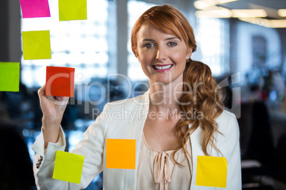 Portrait of businesswoman writing on adhesive notes