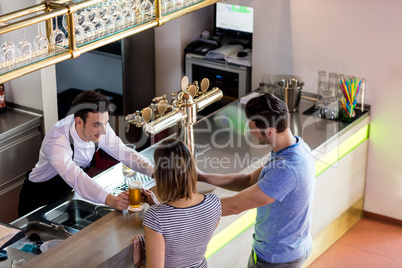 Barkeeper serving beer to couple