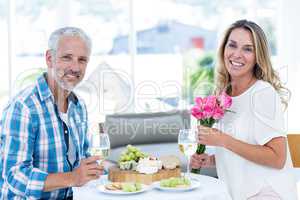 Woman holding roses while having food with husband