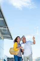 Couple using map against sky in city
