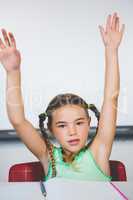 Portrait of schoolgirl raising her arms in classroom