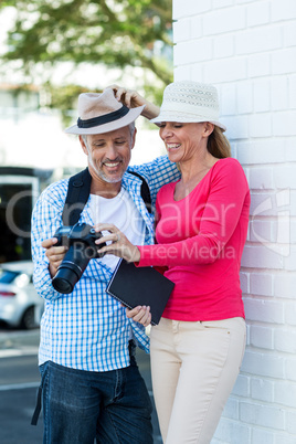 Couple looking in camera while standing by wall