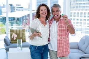 Portrait of smiling mature couple with tablet and house key