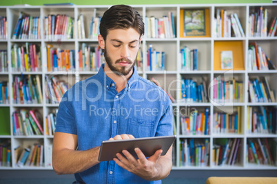 School teacher using digital tablet in library