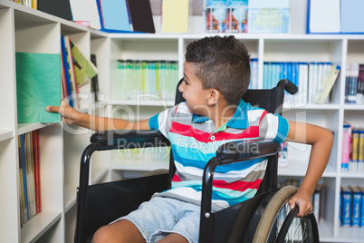 Disabled boy selecting a book from bookshelf in library