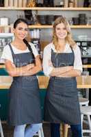 Portrait of two waitresses standing with arms crossed