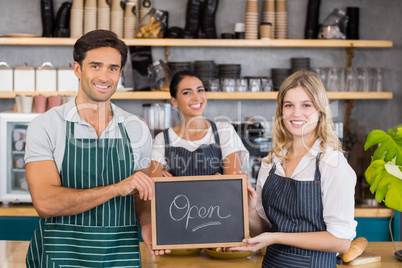 Smiling colleagues showing chalkboard with open sign