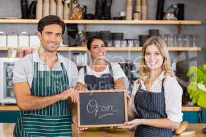 Smiling colleagues showing chalkboard with open sign