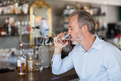 Serious man drinking whiskey at bar counter