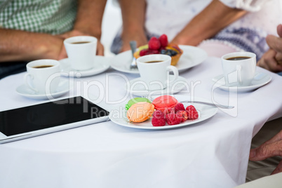 Cropped image of friends sitting by table in restaurant