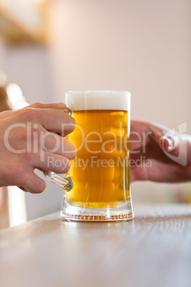 Bartender serving beer to customer at bar counter