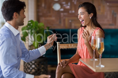 Man proposing to woman offering engagement ring