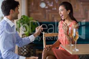 Man proposing to woman offering engagement ring