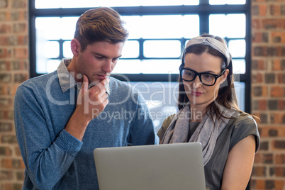 Young colleagues using laptop in office