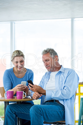 Couple using mobile phone at cafe