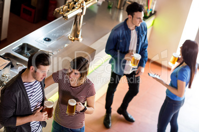 Friends with beer mug by counter in bar