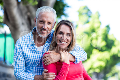 Portrait of romantic couple standing against tree