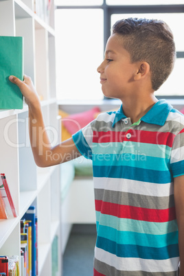 Boy taking a book from bookshelf in library