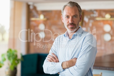 Confident man standing with arms crossed in restaurant