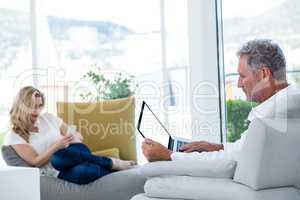 Man using laptop with woman in background