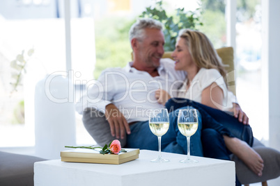 Romantic couple with white wine glasses by rose and gift box on