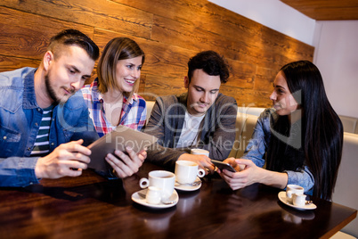 Friends using digital tablet and mobile phone at restaurant