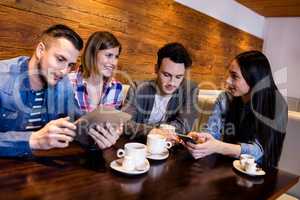 Friends using digital tablet and mobile phone at restaurant