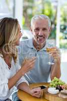 Man holding wineglass while sitting by woman