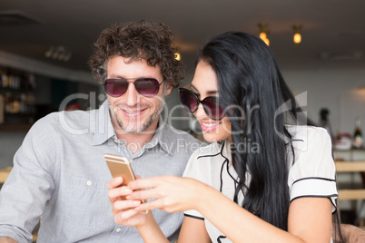 Couple using mobile phone in cafeteria