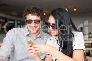 Couple using mobile phone in cafeteria