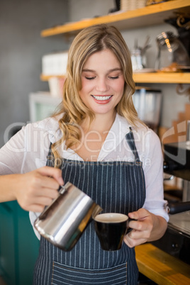 Smiling waitress making cup of coffee