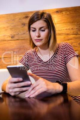 Young woman using cellphone at table