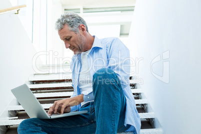 Focused man using laptop on steps