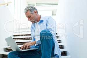 Focused man using laptop on steps