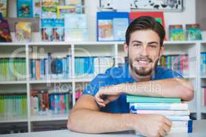 School teacher sitting with books in library