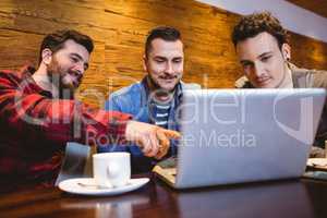 Male friends using laptop at restaurant