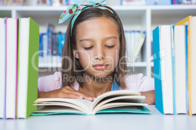 School girl reading a book in library