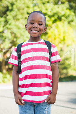 Happy schoolboy standing in campus