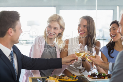 Happy business colleagues toasting beer glasses while having lun